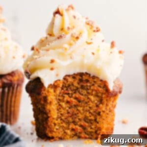 Perfectly frosted carrot cake cupcake with a pecan garnish.