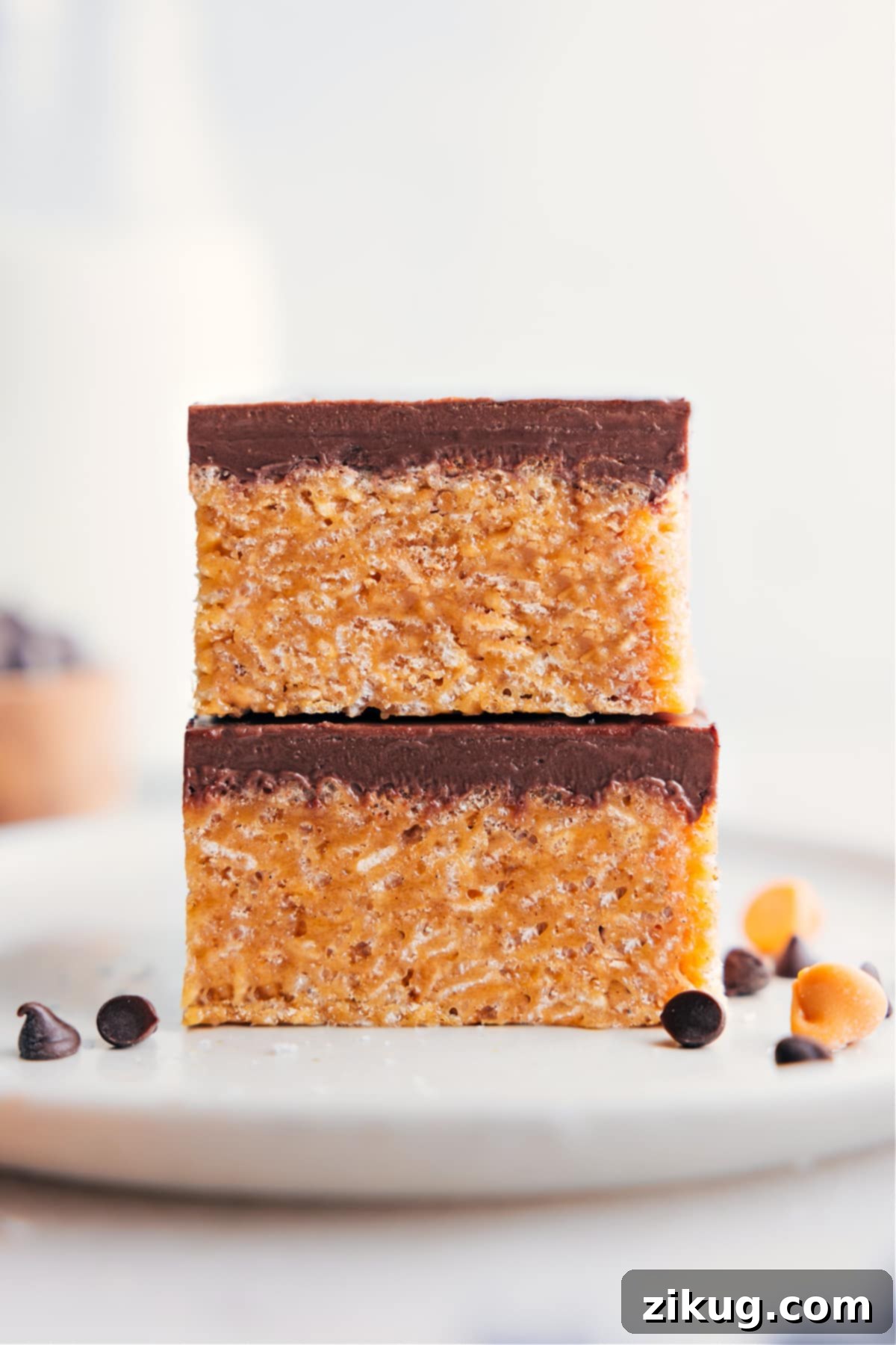 The Best Scotcheroos Recipe Two Scotcheroos bars stacked on top of each other, showcasing their layers of crispy cereal, peanut butter, and chocolate butterscotch topping.