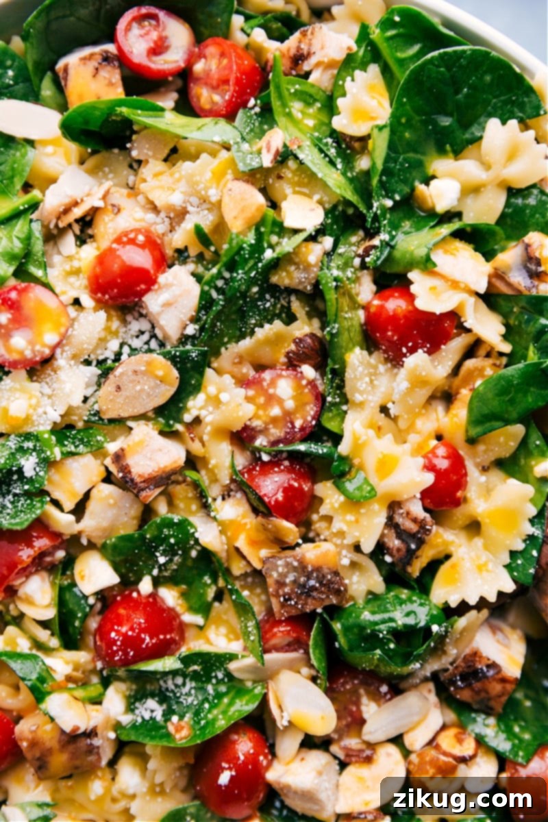 This Chicken Pasta Salad is brimming with goodness, from the rotisserie chicken to the pasta, to the veggies, the dressing and the toasted almonds! Recipe via ChelseasMessyApron. Up close overhead image of the Chicken Pasta Salad brimming with rotisserie chicken, pasta, fresh veggies, zesty dressing, and crunchy toasted almonds.
