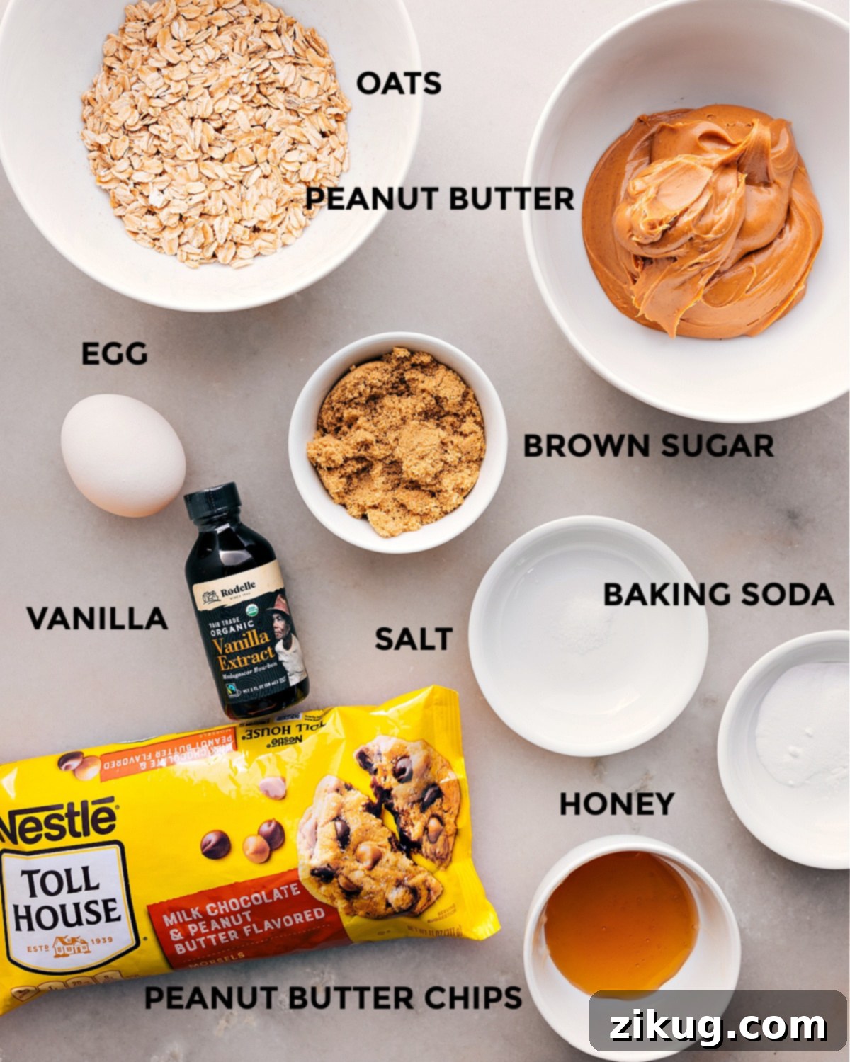All the essential ingredients prepped for easy assembly of healthy breakfast cookies, including old-fashioned oats, creamy peanut butter, honey, brown sugar, baking soda, salt, vanilla extract, a large egg, and peanut butter chocolate chips.