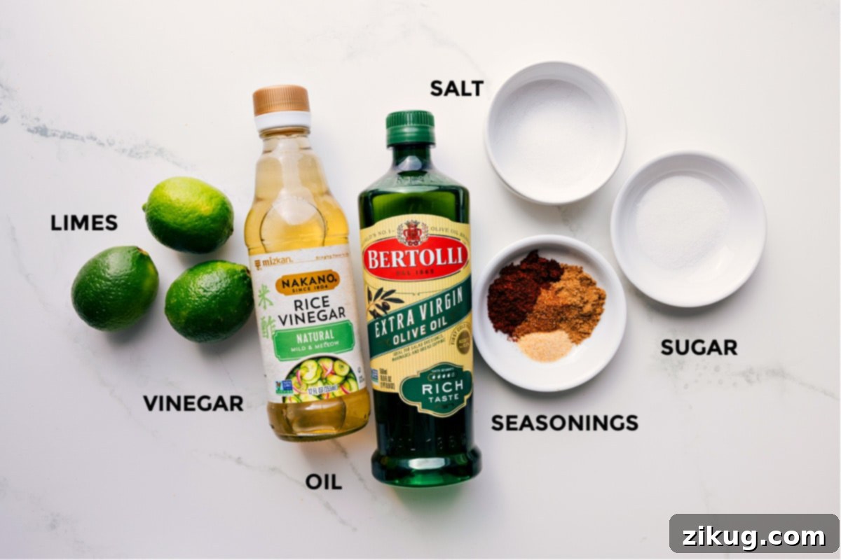 All the dressing ingredients for Mexican Pasta Salad laid out: fresh limes, rice vinegar, olive oil, various seasonings including chili powder and cumin, granulated sugar, and salt.