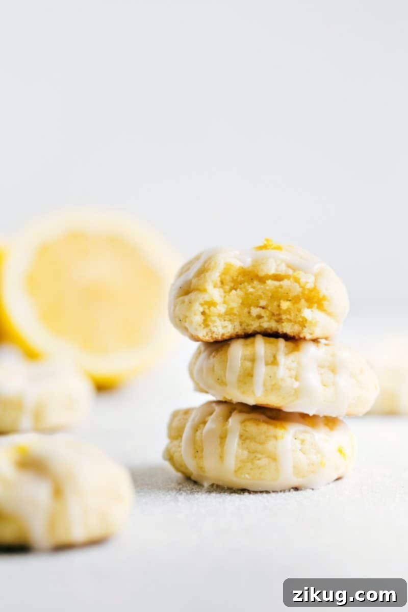 Stacked Lemon Cheesecake Cookies with a Bite Taken Out of One A stack of three lemon cheesecake cookies topped with a delicious frosting with a bite taken from the top cookie.