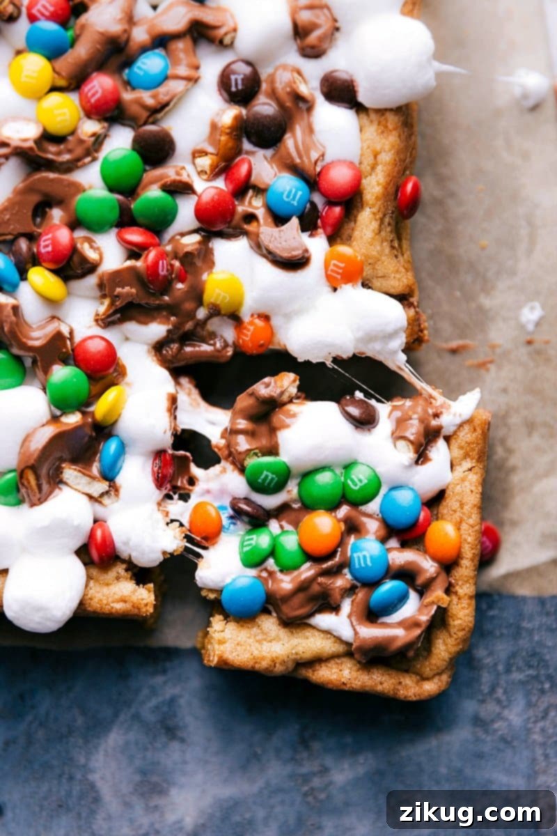 A vibrant close-up of a square Funfetti bar, with a tempting slice removed, showcasing its gooey layers of marshmallow, chocolate, and colorful sprinkles. The textures invite a delicious bite.