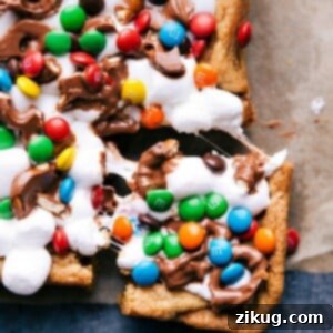 A tantalizing close-up view of perfectly cut Funfetti Bars, showcasing their rich chocolate chip cookie base, gooey melted marshmallows, and colorful array of mini M&M's and sprinkles.