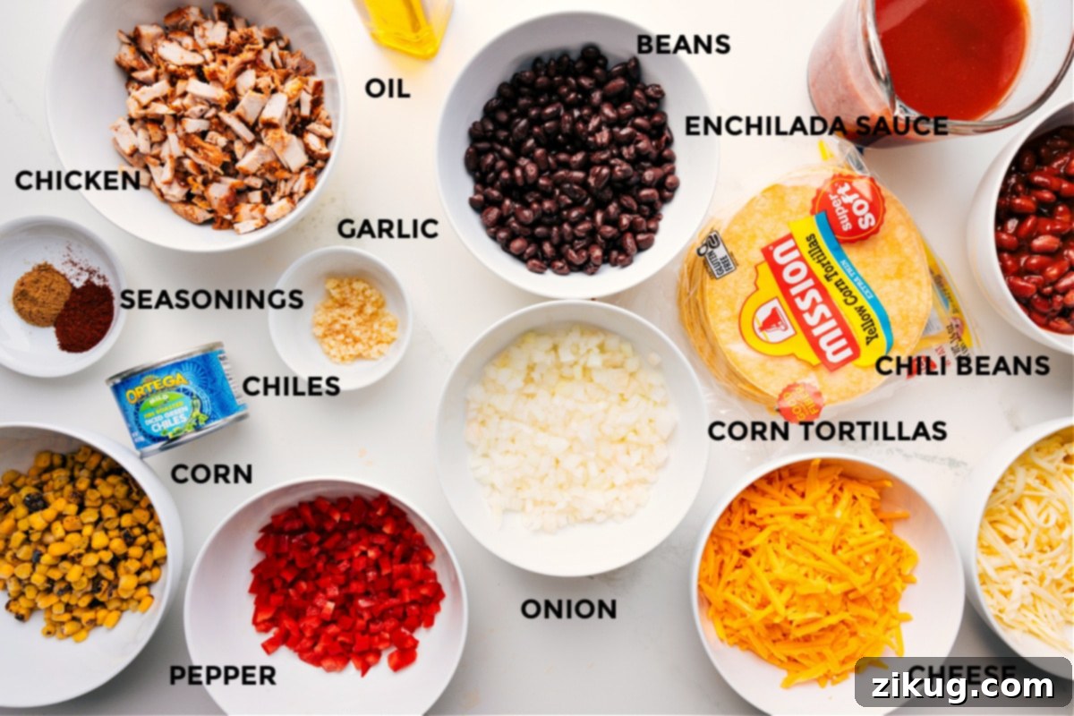 All the ingredients for Chicken Enchilada Casserole prepped and ready to assemble, including chicken, seasonings, corn, peppers, green chiles, garlic, oil, beans, enchilada sauce, chili beans, corn tortillas, onion, and cheese.