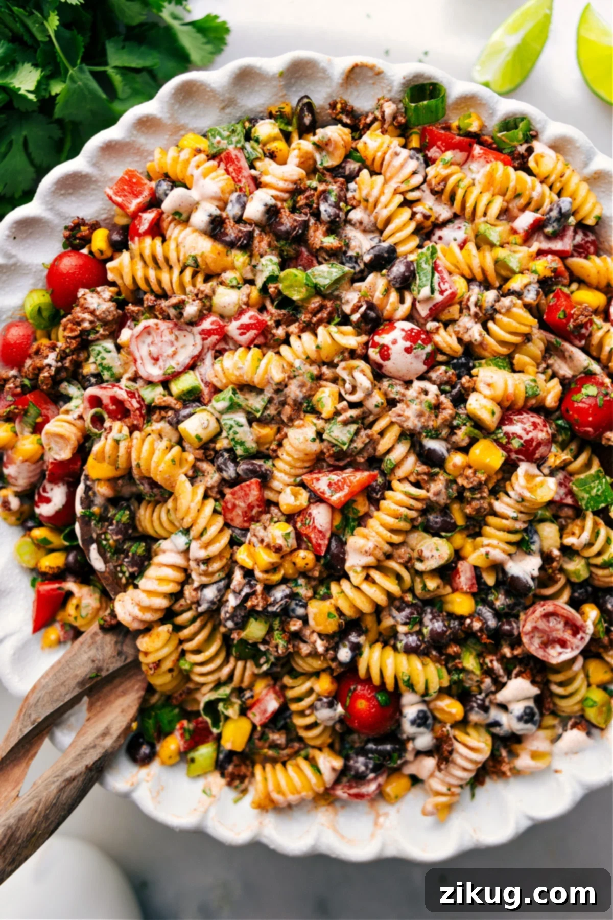 A large bowl of vibrant Taco Pasta Salad, brimming with seasoned beef, colorful vegetables, and pasta, ready to be served. A spoon is poised to scoop a delicious portion.
