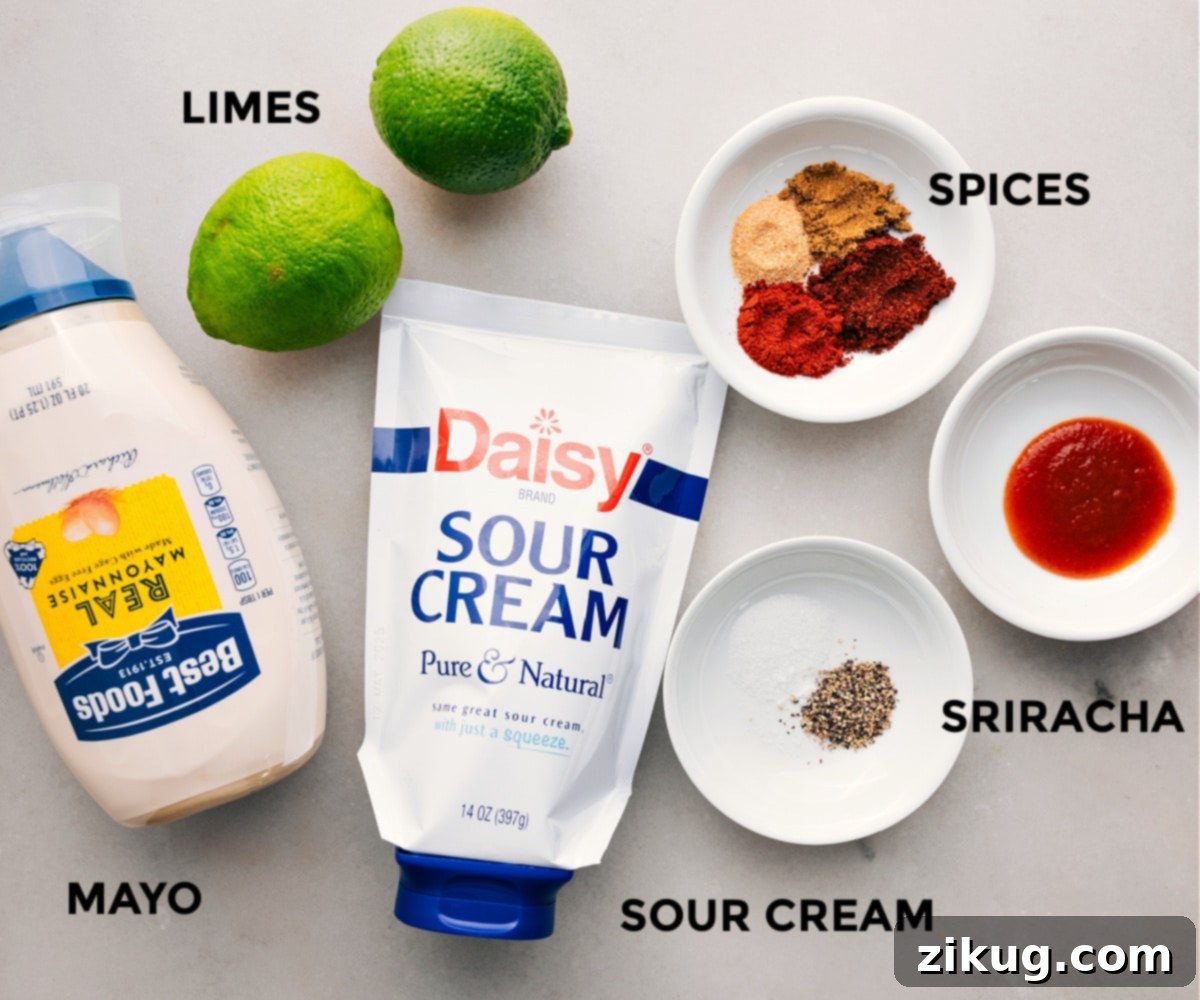 All the creamy dressing ingredients for Taco Pasta Salad, including mayonnaise, sour cream, fresh limes, and a selection of spices, are arranged on a white surface, ready to be mixed.