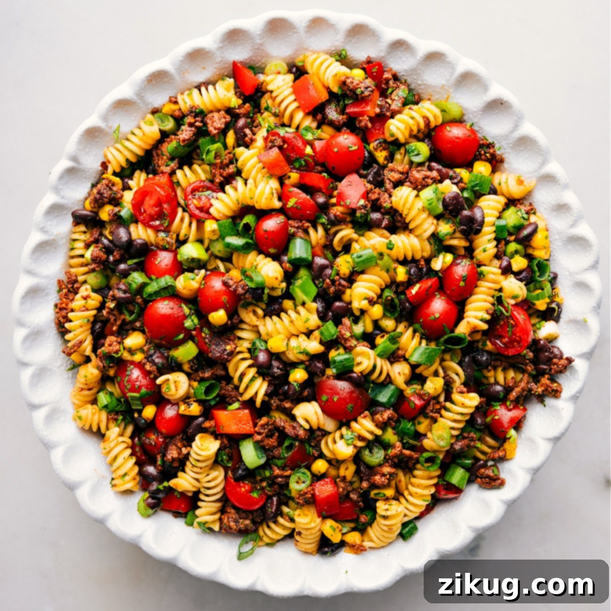 A large serving bowl filled with a tossed Taco Pasta Salad, with its ingredients vibrant and well-distributed, ready for the final touch of creamy dressing.