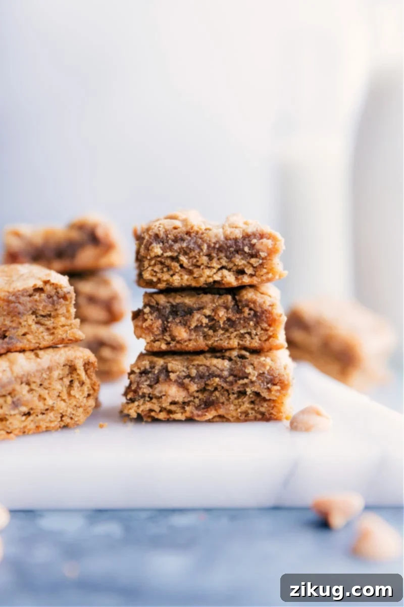 Deliciously healthy Peanut Butter Banana Bars made with overripe bananas, peanut butter, and honey. No butter, oil, or white flour needed for these fudge-like, chewy treats. Image of the peanut butter banana bars stacked on top of each other, showcasing their fudgy texture and golden-brown tops.