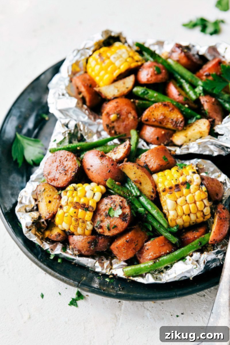 Easy Foil Pack Garlic Butter Sausage & Veggies! A quick, delicious, and simple meal with smoked sausage, red potatoes, sweet corn, and crisp green beans. Prepped in 15 minutes, perfect for grill or oven. #dinner #quick #easy #simple #camping #overfire #grilled #garlicbutter #sausage #veggies #foilpacks Garlic Butter Sausage & Veggie foil packs, perfectly cooked and ready to serve.