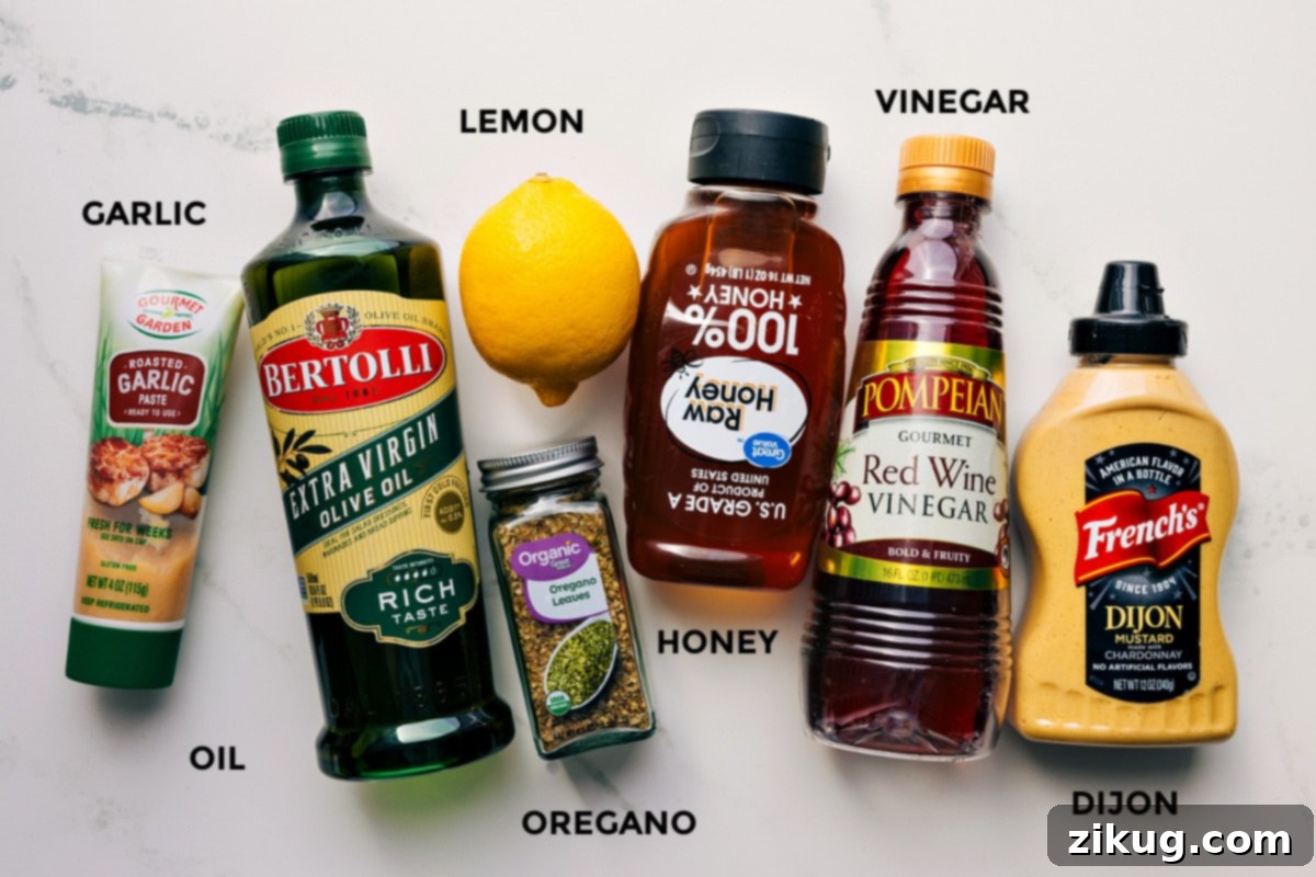 All the vibrant dressing ingredients prepped for easy assembly, including minced garlic, high-quality olive oil, fresh lemon, dried oregano, a touch of golden honey, red wine vinegar, and creamy Dijon mustard.