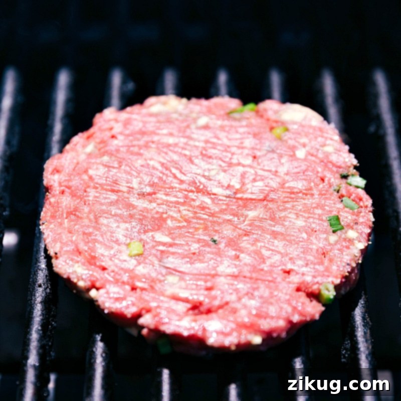 Grilling Beef Patty to Perfection A beef patty sizzling on the grill, being cooked to perfection, ensuring a juicy and flavorful patty.