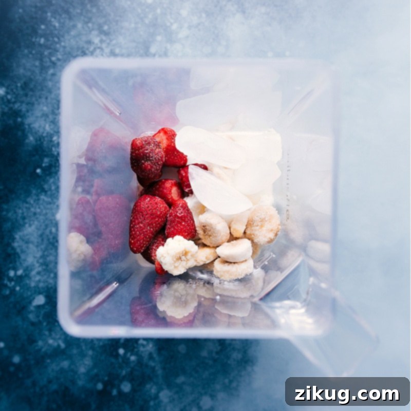 The perfect blend starts here: All Jamba Juice Strawberry Wild ingredients in the blender, ready for a creamy, thick, and delicious smoothie. An overhead shot of fresh and frozen ingredients being added into a high-powered blender, ready to be processed into a smoothie.