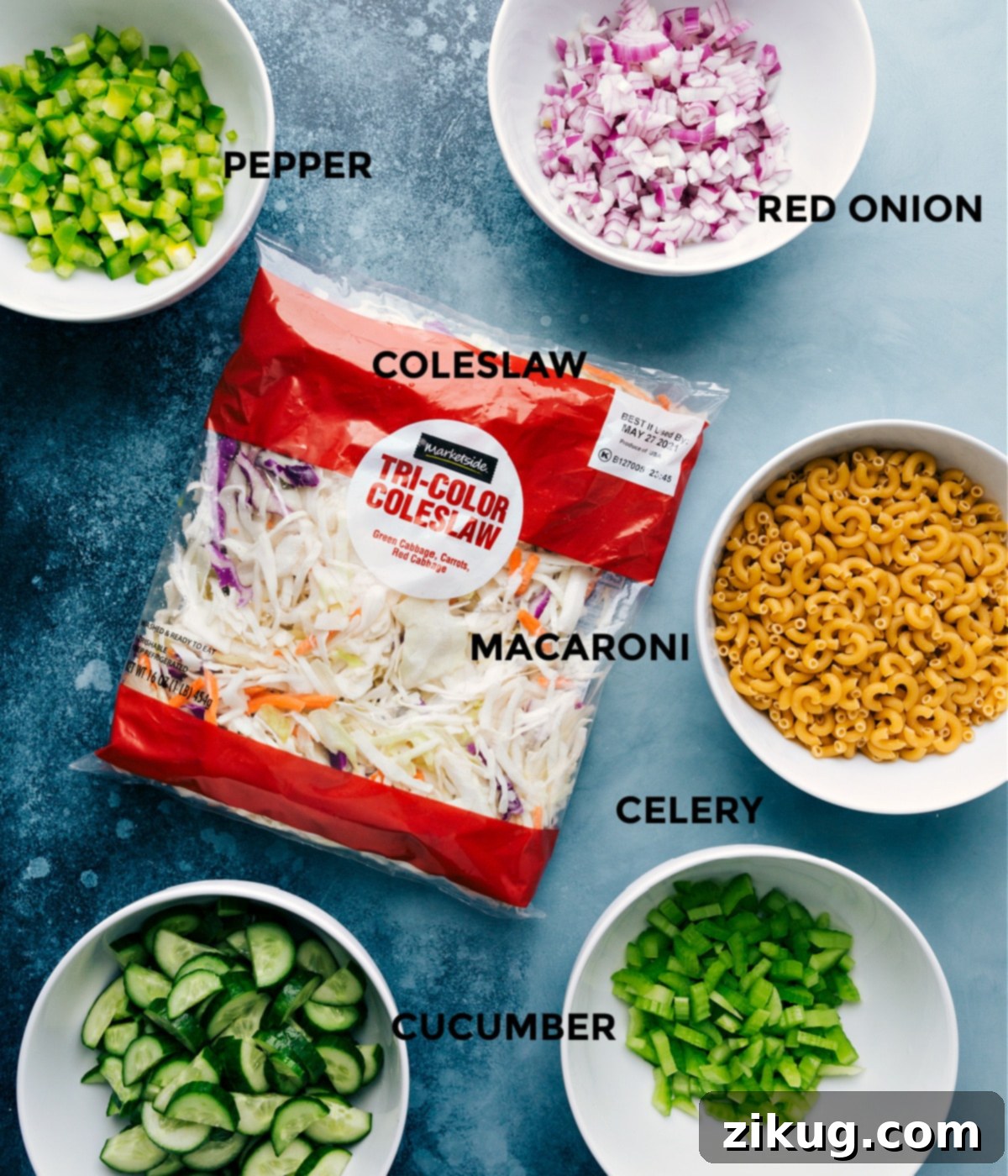 All the fresh ingredients for Macaroni Coleslaw Salad prepped and laid out for easy assembly, including pasta, cabbage mix, and diced vegetables.