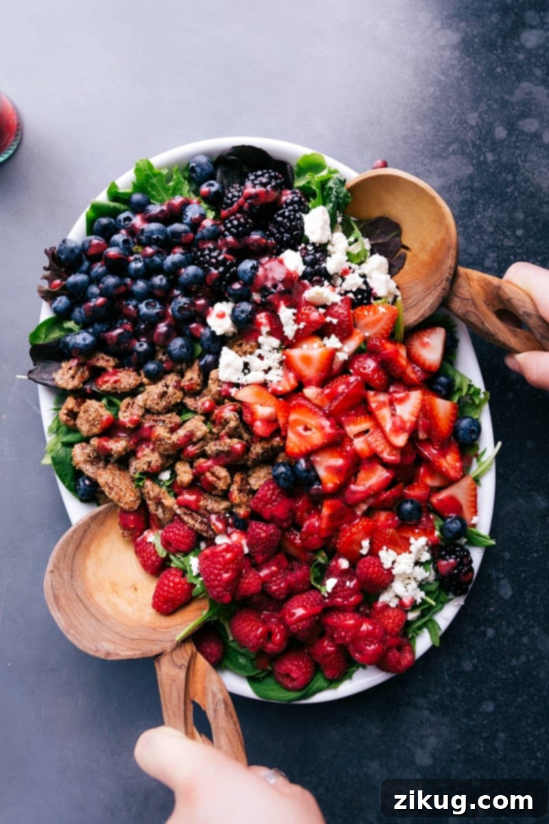 A refreshing raspberry salad, brimming with fresh fruit, creamy feta, and crunchy candied pecans, waiting to be dressed.