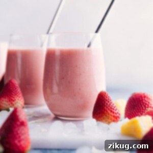 Close-up of a Strawberry Piña Colada smoothie in a glass, garnished with a fresh strawberry.