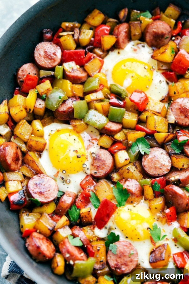Ready-to-serve one-pan sausage and veggie hash with perfectly cooked eggs on top, garnished with fresh herbs.