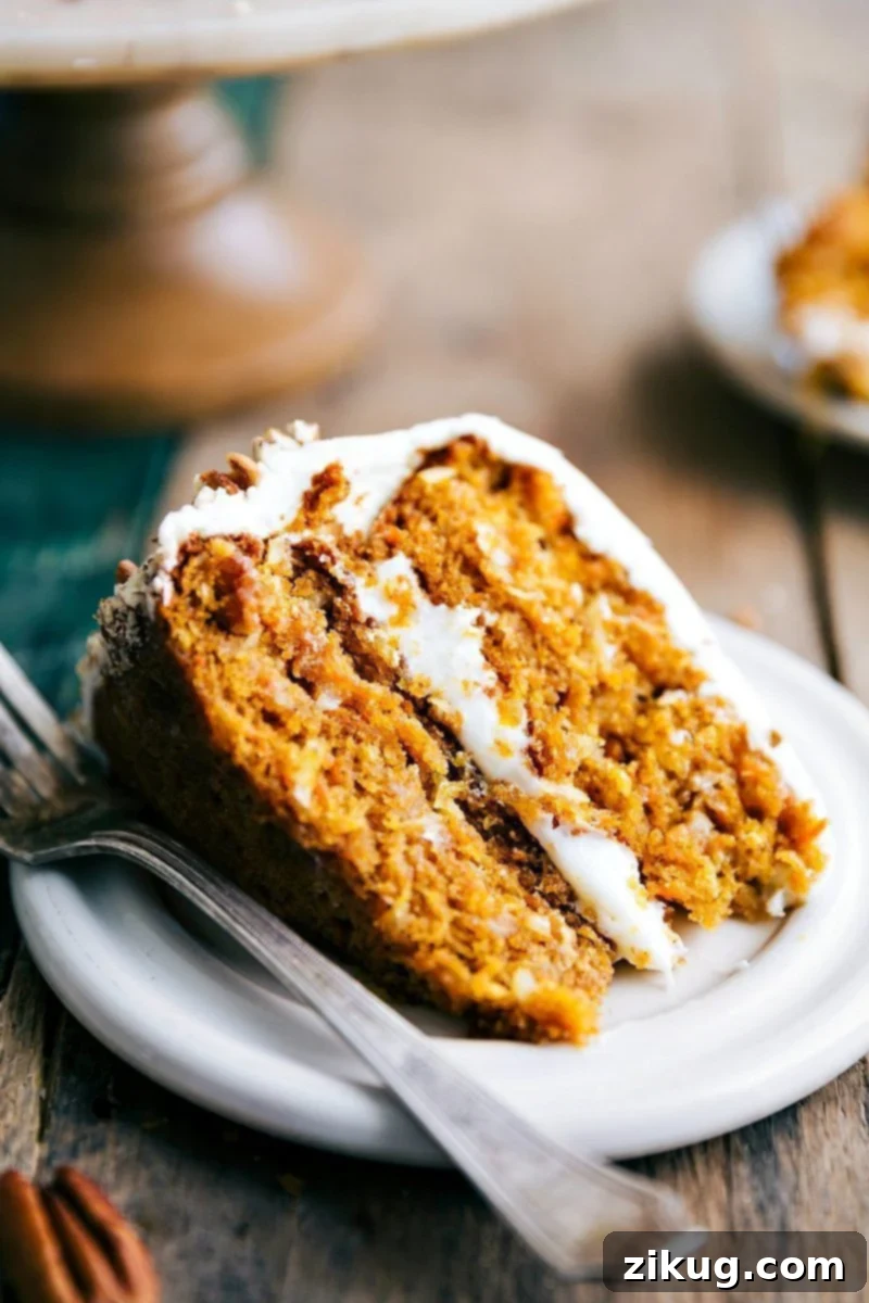 Moist Pumpkin Carrot Cake Slice with Icing A beautifully moist slice of Pumpkin Carrot Cake, topped with creamy white icing, showcasing its soft interior and inviting texture.