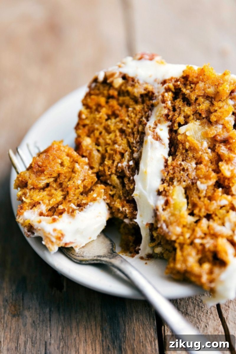 Flavorful Pumpkin Carrot Cake Slice with Icing and a Bite Taken A close-up of a delightful slice of pumpkin carrot cake, showing a bite taken, revealing its rich, moist texture and the generous layer of cream cheese icing.