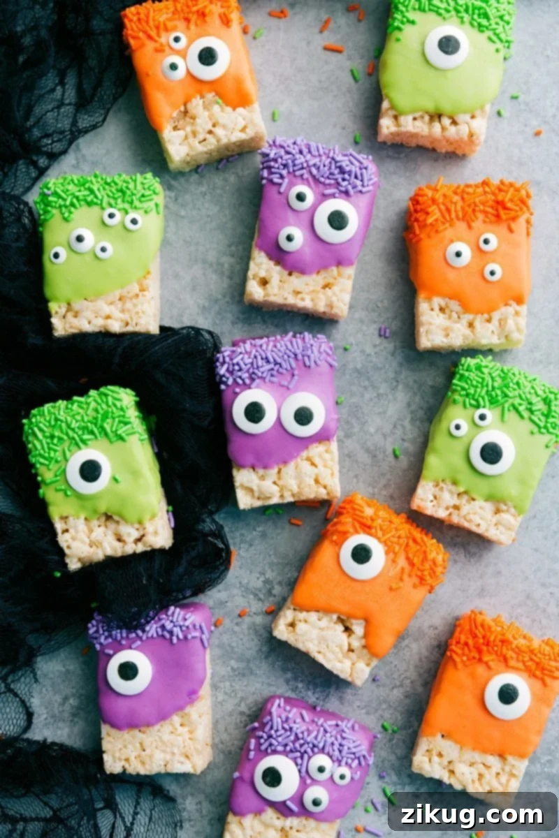 Close-up of a platter showcasing spooky yet delicious 3-ingredient Halloween treats including Monster Rice Krispies with candy eyes, chocolatey Peanut Butter Spider Cookies, ghost-shaped Nutter Butter treats, and green Witch Finger Pretzels.