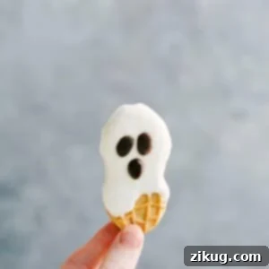 A playful Nutter Butter ghost cookie with a white chocolate coating and a simple chocolate chip face.