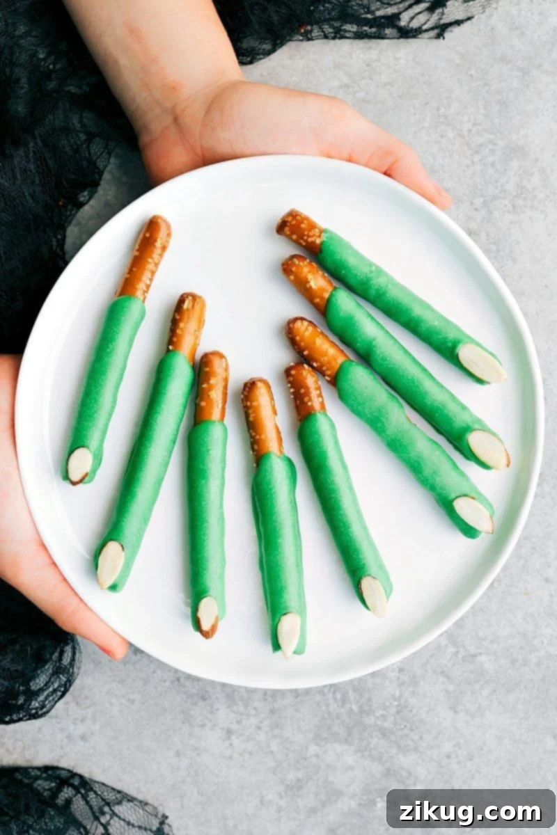 Creepy yet fun Witch Finger Pretzels made with green candy melts and a sliced almond nail, perfect for Halloween.