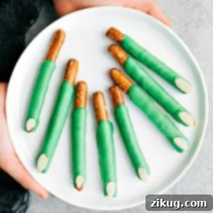 A plate of eerie green witch finger pretzels with almond nails, ready for Halloween snacking.