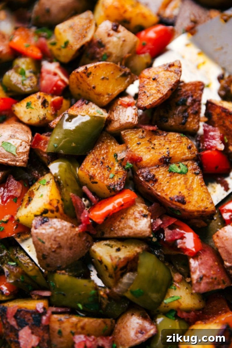 Easy One Pan Bacon and Potatoes 6 Freshly chopped red potatoes, colorful bell peppers, and yellow onion generously tossed with herbs and spices on a sheet pan, ready for the oven.