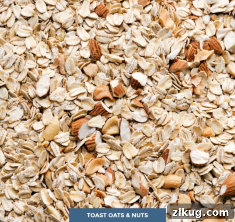 Toasting Oats and Nuts for the Recipe Old-fashioned oats and various nuts, the primary ingredients for the granola bar recipe, are neatly arranged and prepared for toasting in the oven, ensuring optimal flavor.