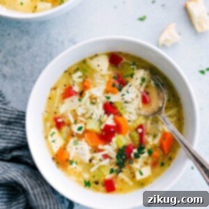 A steaming bowl of comforting Chicken Rice Vegetable Soup, garnished with fresh herbs, ready to be enjoyed.
