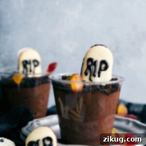 A graveyard pudding cup with crushed cookies, a Milano tombstone, and gummy worms