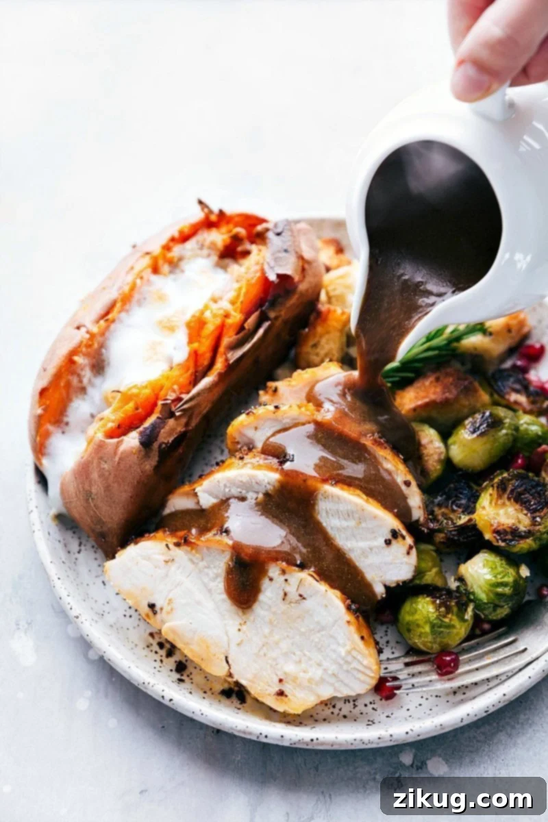 Pouring Gravy Over Freshly Prepared Thanksgiving Dinner from Sheet Pans Gravy being poured over a freshly cooked Thanksgiving dinner plate, featuring a meal prepared on two sheet pans.