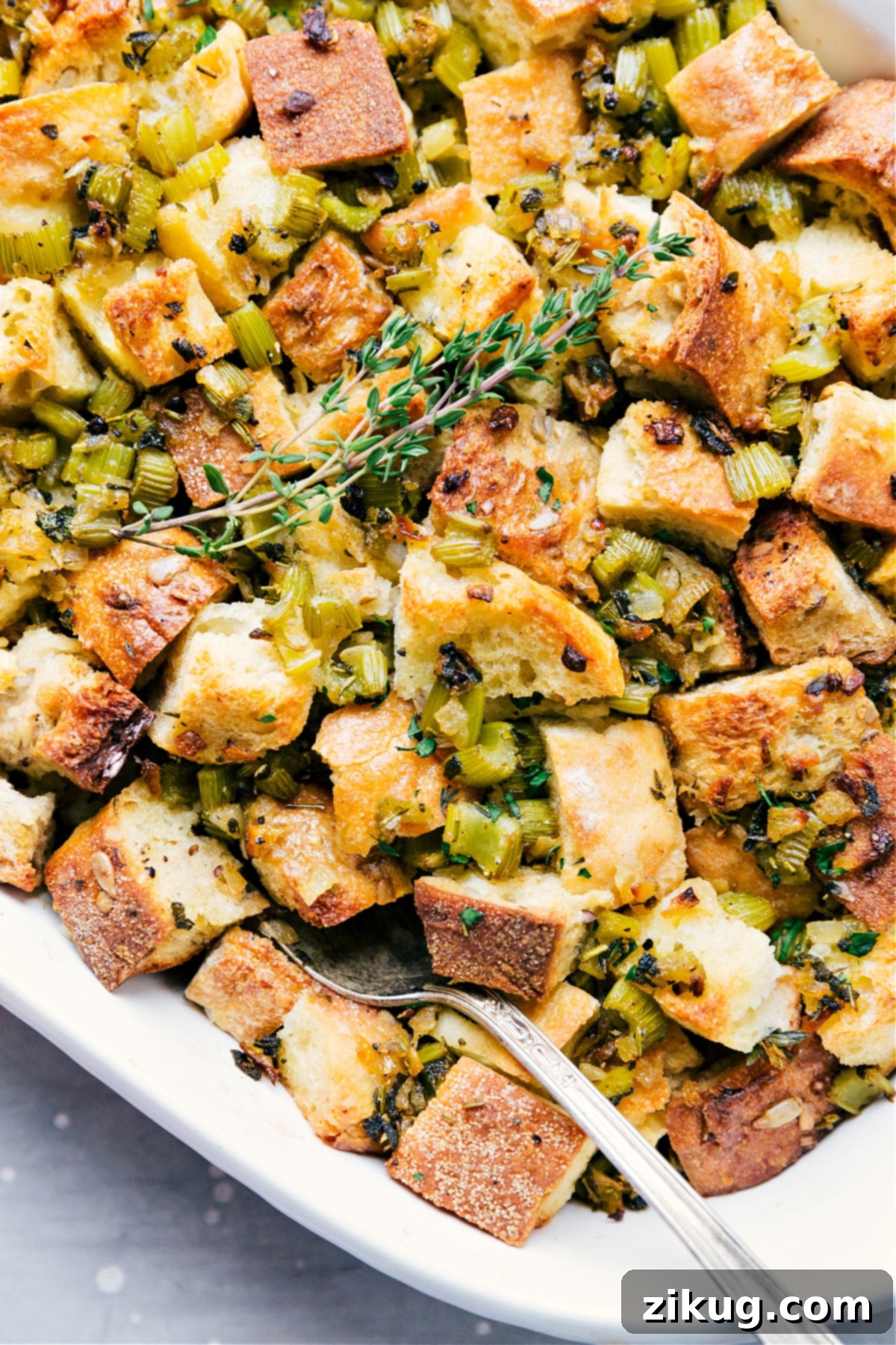 A freshly baked Thanksgiving dressing, scooped with a spoon, revealing its moist, herb-infused interior and golden-crisp top layer, ready to be enjoyed.