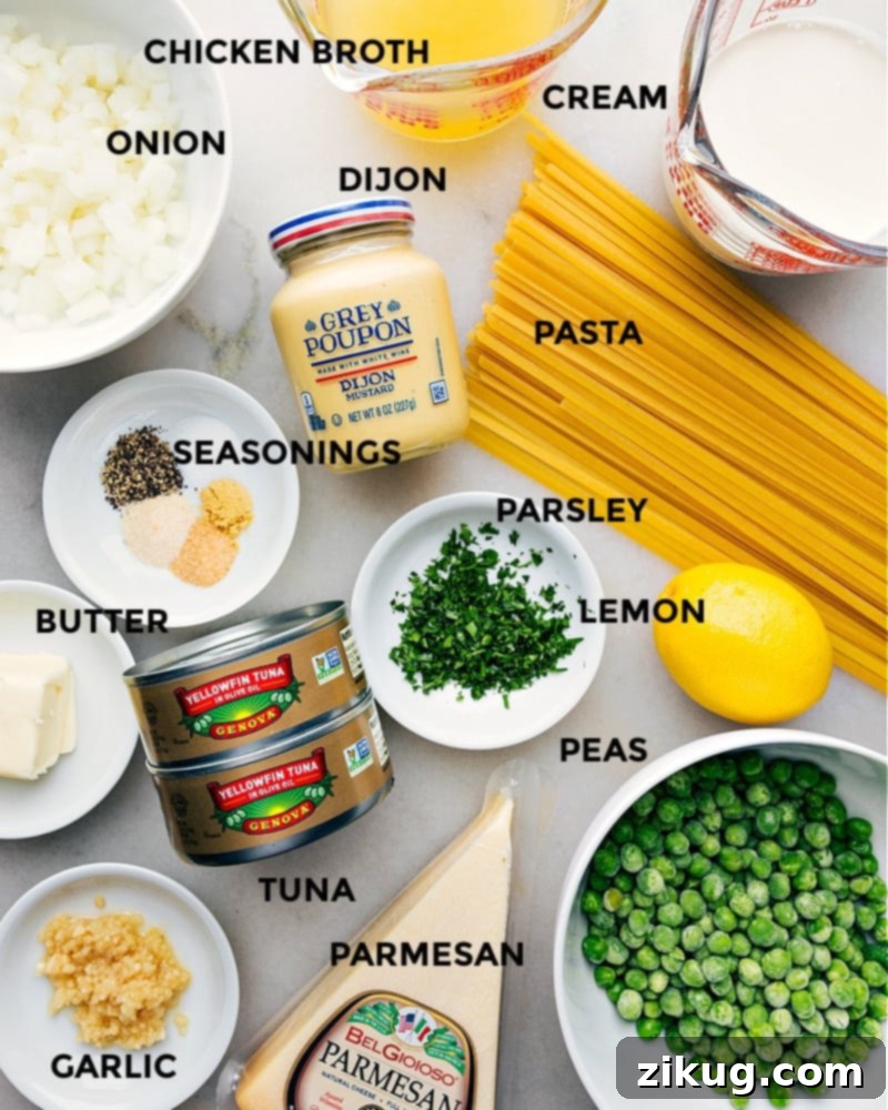All the fresh ingredients for Creamy Tuna Pasta: pasta, tuna, peas, butter, onion, garlic, broth, cream, parmesan, and seasonings, neatly arranged. Ingredient shot- image of the ingredients used in this creamy tuna pasta dish laid out on a wooden table, including pasta, tuna cans, peas, and fresh aromatics.
