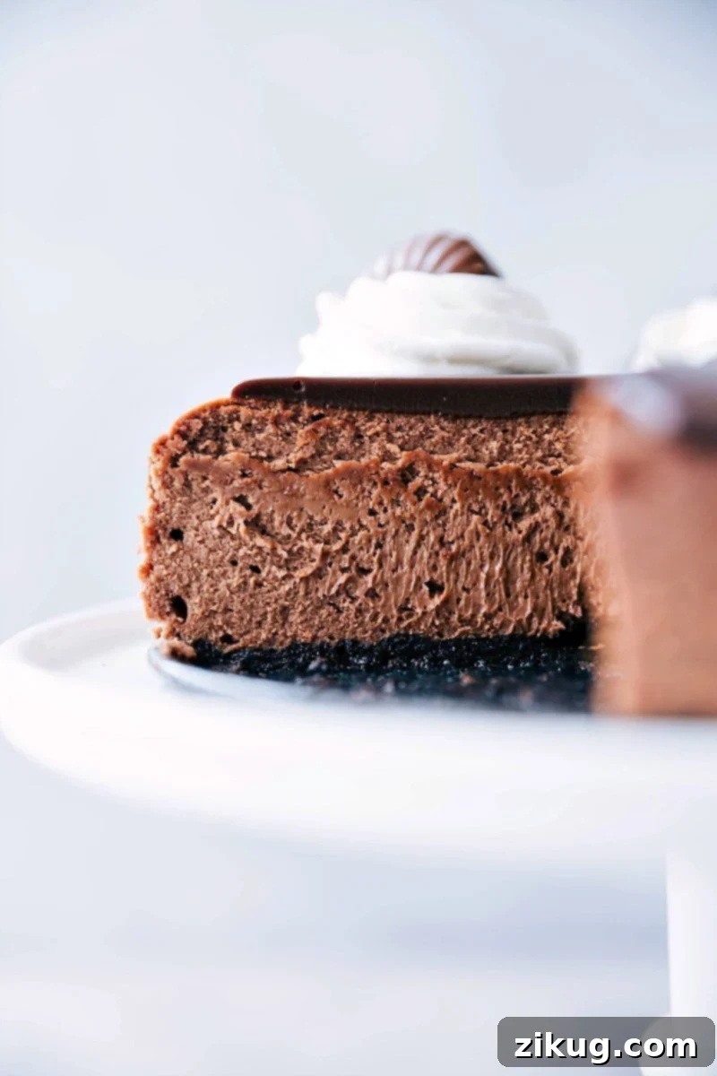A slice of Chocolate cheesecake with a ganache topping on a white plate