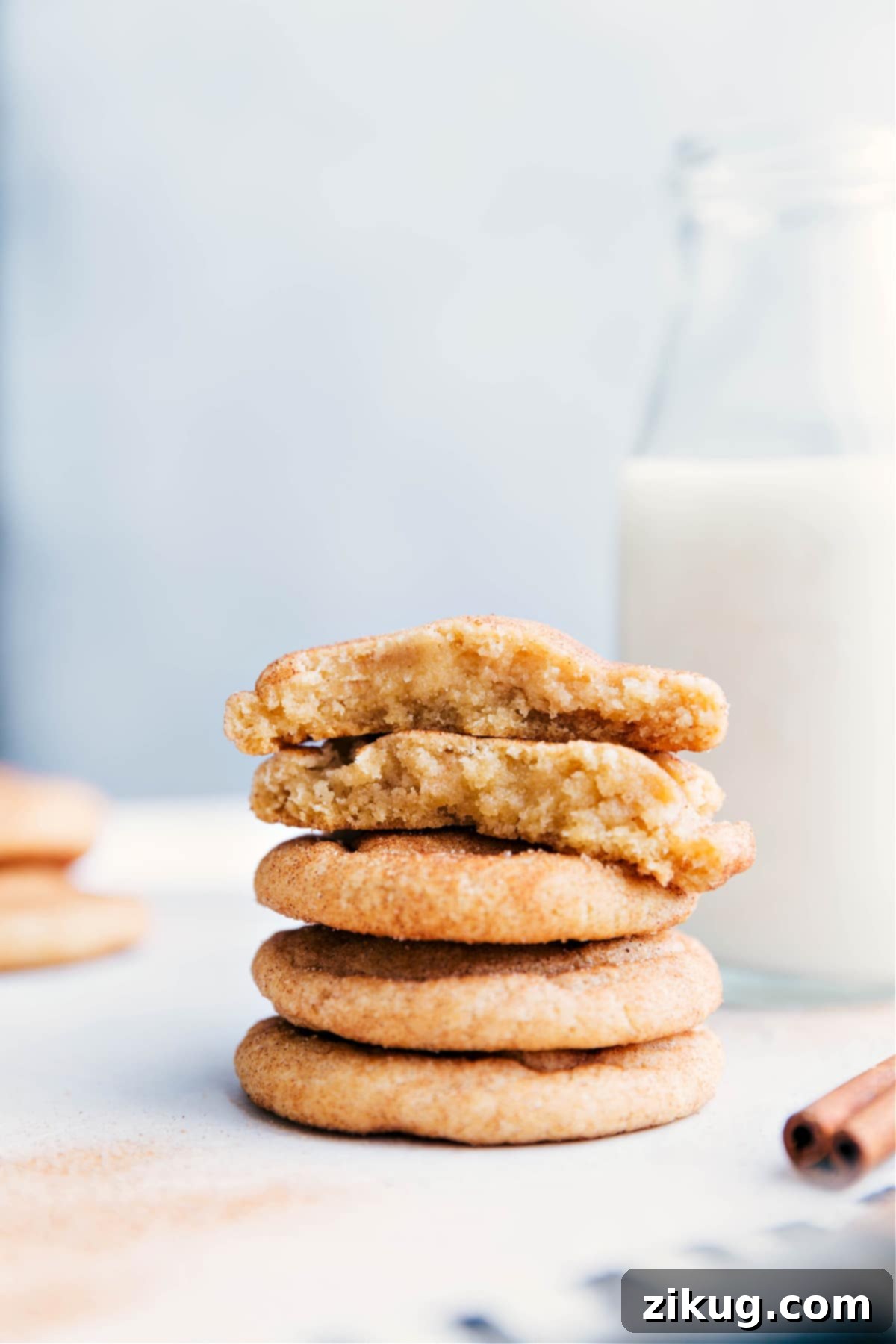 Fresh Snickerdoodle Cookies on Plate Stack of freshly baked snickerdoodle cookies on a plate, with one broken in half to reveal the soft and delicious interior.