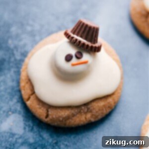 A close-up of a finished Melted Snowman Cookie, showing the details of its peanut butter cup head, white chocolate 'snow,' and candy face.