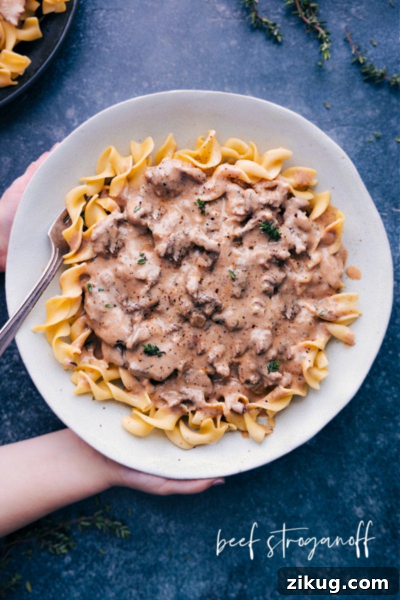Hearty Instant Pot Beef Stroganoff: Tender beef in creamy sauce with egg noodles, ready in minutes. Overhead shot of a serving of Instant Pot Beef Stroganoff with tender beef slices and creamy sauce over egg noodles, garnished with fresh herbs.