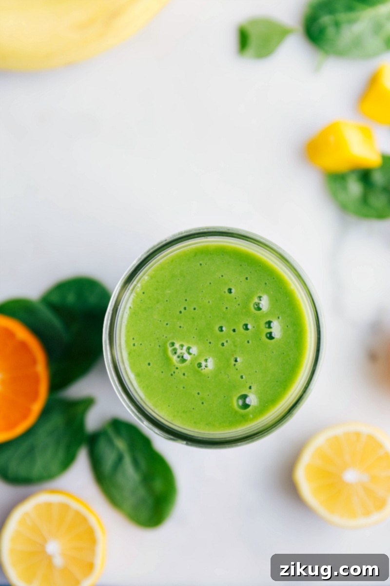 A beautifully presented healthy green smoothie in a tall glass, garnished with a fresh lemon slice and surrounded by lush spinach leaves and citrus fruits, inviting a refreshing sip.