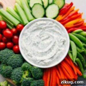 Homemade Veggie Dip in a white bowl with an assortment of fresh vegetables arranged artfully around it on a wooden board.