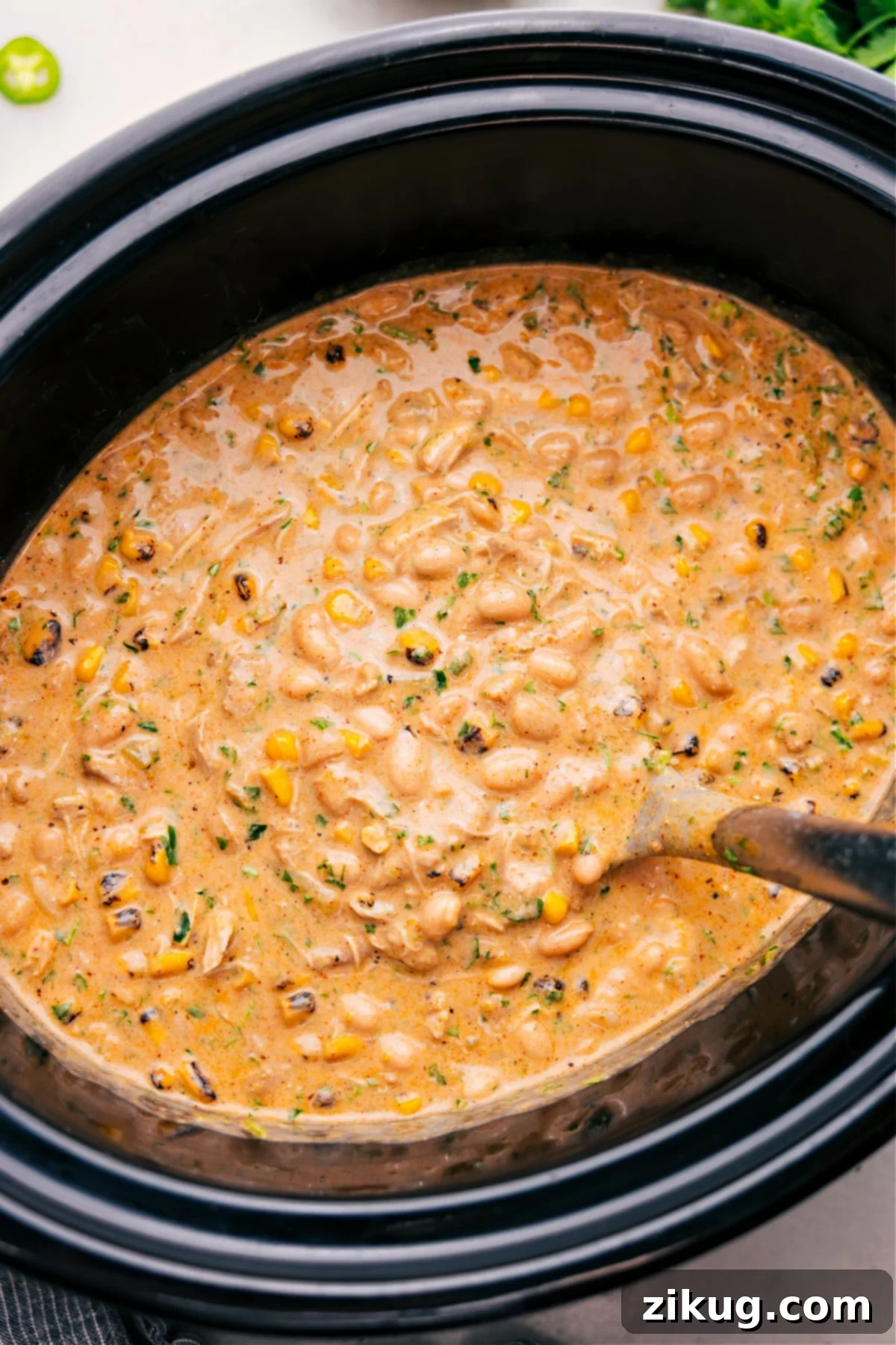 The Best Crockpot White Chicken Chili Recipe Crockpot White Chicken Chili cooks in the slow cooker, creating a warm and inviting meal.