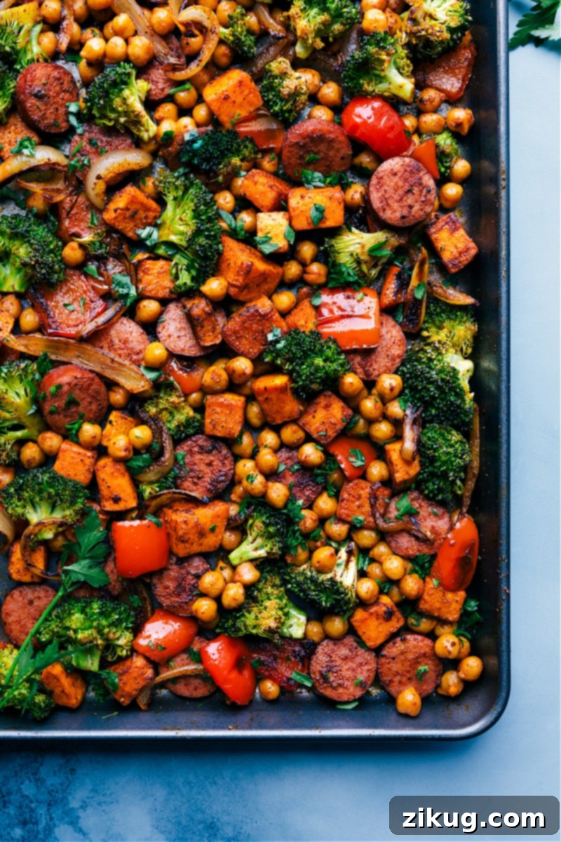 The ultimate One-Pan Sausage and Chickpeas, straight from the oven! This healthy, flavorful meal, seasoned with Mexican-inspired spices and featuring vibrant vegetables, is a testament to quick prep and even quicker cleanup. #sheetpandinner #healthymeal #sausageandveggies #easyrecipe Overhead image of a sheet pan filled with freshly roasted Sausage and Chickpeas and vegetables, ready to serve