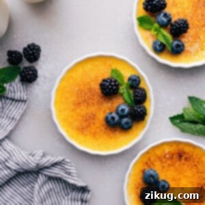 Golden creme brûlées with a crisp sugary top, garnished with fresh fruit, ready to be enjoyed.