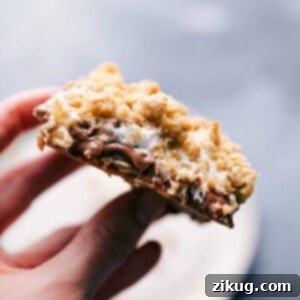 Holding a s'mores cookie bar, displaying its gooey and irresistible inside.