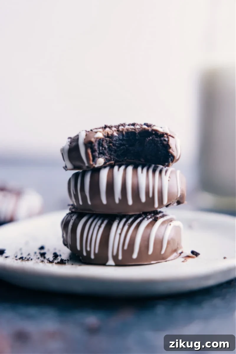 Image of the Oreo Truffles stacked on top of eachother, beautifully coated in chocolate with a white chocolate drizzle.