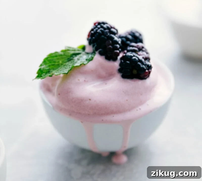 Jazz up the Strawberry Frozen Yogurt with lots of add ins like fresh berries and other exciting toppings! This healthy and easy ice cream maker recipe is via chelseasmessyapron #dessert #quick #easy #simple #best #healthier #icecreammaker #strawberry #frozen #yogurt A vibrant bowl of Strawberry Frozen Yogurt generously topped with a colorful assortment of fresh berries, including strawberries, blueberries, and raspberries, enhancing its appeal.