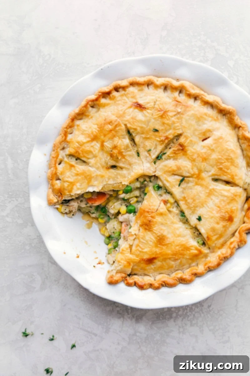 A golden-crusted homemade chicken pot pie, with a slice removed to reveal the steaming, creamy filling inside, ready to be served and savored.