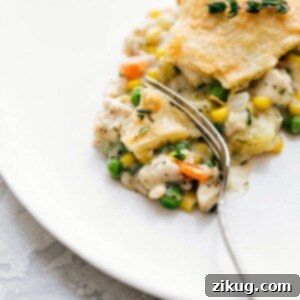 A savory and flavorful chicken pot pie on a plate, with a bite taken out to reveal its creamy center filled with chicken and vegetables, inviting you to enjoy this hearty meal.