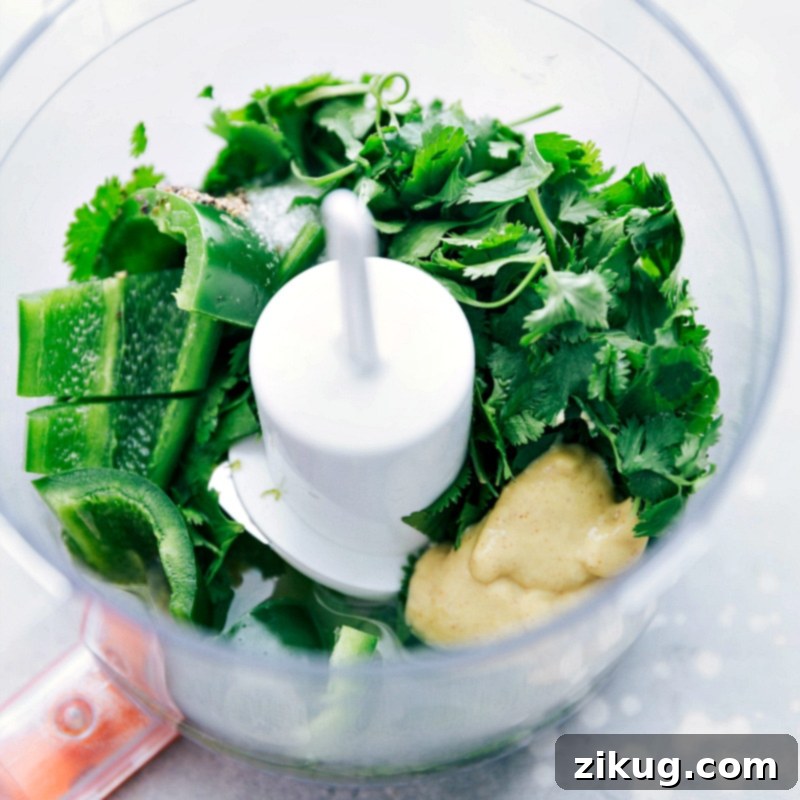 A vibrant green cilantro-lime vinaigrette being freshly prepared in a mini food processor, showcasing the zesty dressing that will perfectly complement the Southwest Quinoa Salad and elevate its flavors.