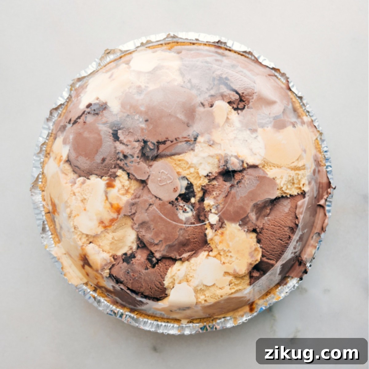 How To Make Ice Cream Pie A completed ice cream pie, covered with its clear plastic lid, securely placed in the freezer to solidify and chill before serving.
